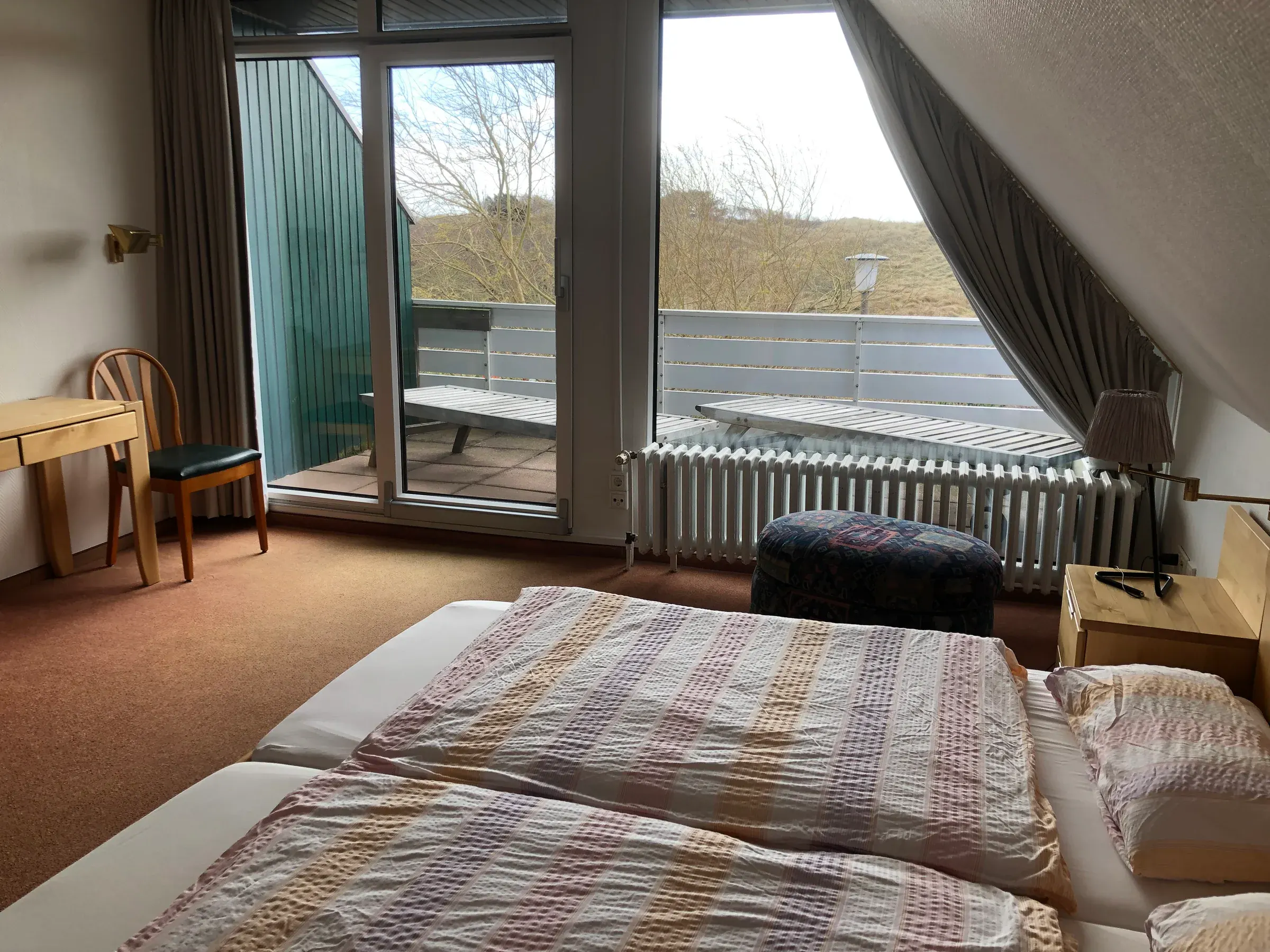 Schlafzimmer der Ferienwohnung Borkum mit großen Fenstern und Balkonzugang